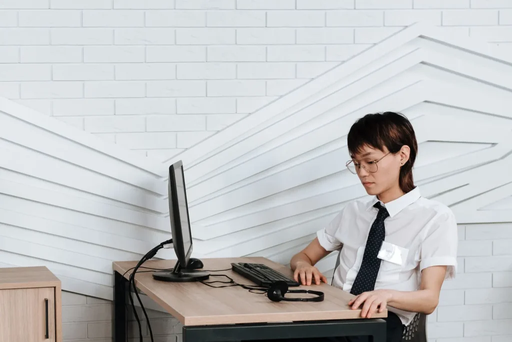Irodai dolgozó ergonomikus íróasztalnál ül monitor előtt, gerincbarát munkakörnyezetben